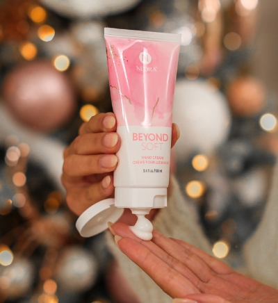 Hand putting box of Beyond Soft Hand Cream in pink stocking.